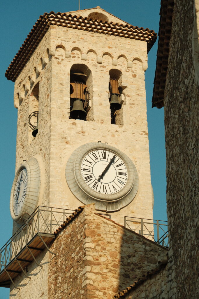 La photographie montre la tour de l'horloge au centre, illuminée par une lumière dorée.